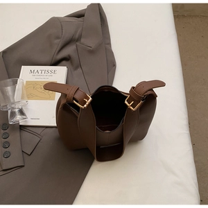 Detail view of smooth dark brown leather tote with adjustable gold buckle straps