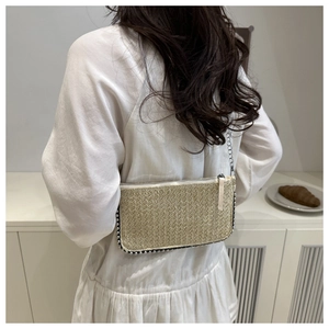 Detail einer gewebten Strohhandtasche mit silbernem Perlenrand und Metallkettenriemen