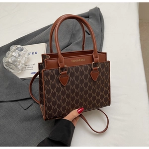 Nahaufnahme der Retro-Umhängetasche mit Monogramm-Muster und braunem Lederbesatz