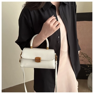Detail of a white crossbody bag with vintage gold metal buckle on a shoulder-strap