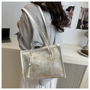 Detail of white butterfly print tote bag with elegant tassels in a modern office setting