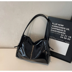 Detail of black glossy patent leather tote bag with drawstring accents and slim shoulder straps