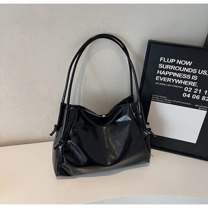 Detail view of glossy black faux leather shoulder bag with side knot and magnetic clasp