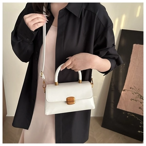 Close-up of elegant white square handbag with vintage gold metal clasp on a model