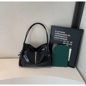 Detail of a high-gloss black tote bag showing size scale next to a tablet device