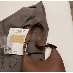 Detail of brown matte leather Hobo bag featuring vertical stitching and adjustable strap