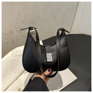 Detail of minimalist black hobo bag with silver buckle held against a white blazer