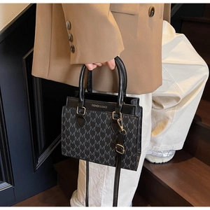 Detail der schwarzen Umhängetasche mit M-Muster und goldenem Fashion & Bags Schriftzug