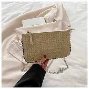 Detail der khakifarbenen Stroh-Handtasche mit Silberkette und Nietenverzierung