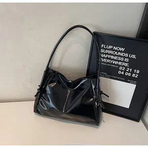 Close-up of a black glossy leather tote bag with knot details and a modern minimalist finish