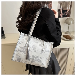 Detail of silver tote bag with grey butterfly print and silk tassel on model