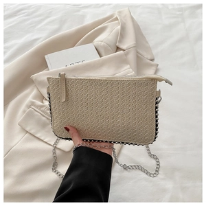 Detail einer beige Strohkupplung mit Silberperlenbesatz und abnehmbarer Metallkette