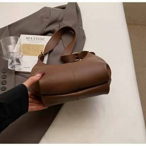 Detail of dark brown matte leather tote bag featuring double-layered base and metal buckle