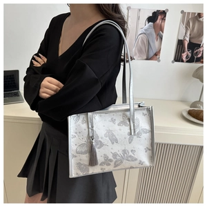 Details der silbergrauen Schmetterlings-Tasche mit Quaste und schmalem Schultergurt