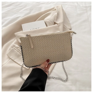 Detail der beige geflochtenen Clutch mit silbernen Metallperlen und Kettenriemen