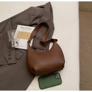 Detailed view of a brown semi-circle hobo bag with adjustable strap in urban setting
