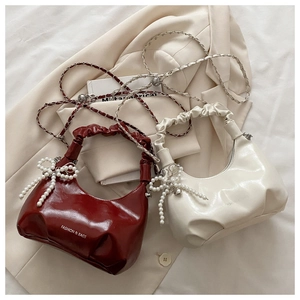 Detail of hobo bags with pleated handles, pearl bow charms and chain straps