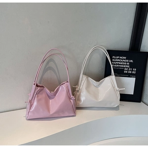 Detail of minimalist faux leather tote bag showing side knot design and slim straps