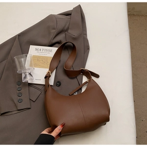 Detail view of a coffee brown faux leather hobo bag with adjustable strap and gold hardware