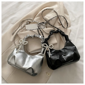 Close-up of ruched handle with pearl bow decoration and chain strap detail on handbag