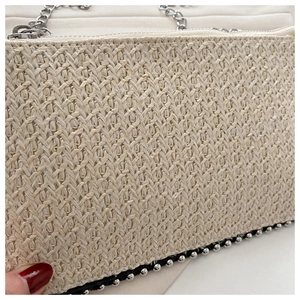 Detail der gewebten Strohtasche mit Metallperlenbesatz und silbernem Kettengurt
