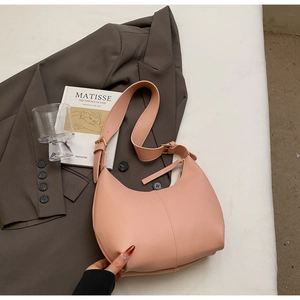 Detailed close-up of pink leather hobo bag with gold buckle on dark blazer background