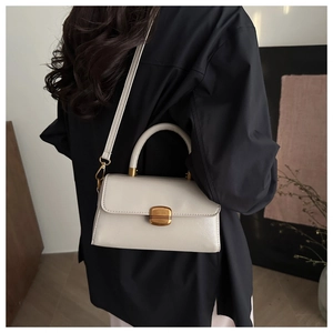 Detail of cream white faux leather handbag with vintage gold buckle and top handle