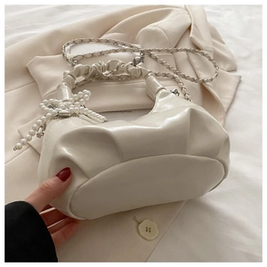 Detail of off-white pleated cloud bag with elegant pearl bow and gold chain strap