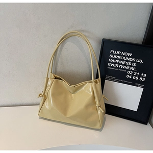 Detailed view of cream-colored glossy leather tote bag with elegant side knot handles