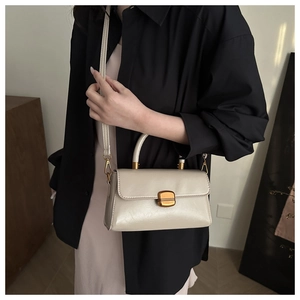 Detail of cream vintage crossbody bag with gold turn-lock and adjustable shoulder strap