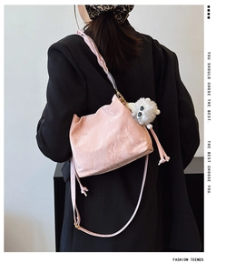 Detailed back view of pink pleated bucket bag with braided strap and plush monster charm