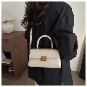 Detail of cream leather handbag with gold twist lock on black shirt model back