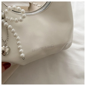 Detail of cream pleated crossbody bag with pearl chain and heart metal pendant