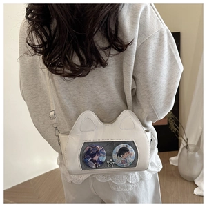 Detail view of white cat-ear ita bag with transparent window and decorative pins