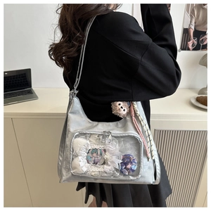 Detail of silver Ita bag with clear PVC window showcasing anime badges and lace trim