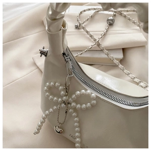 Detail of cream white bag with pearl bow, heart pendant and silver chain strap