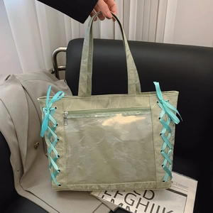 Detail of light green tote bag with blue ribbon lacing and clear PVC window