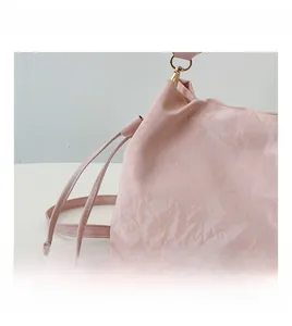 Macro detail of soft pink wrinkled faux leather bag with elegant gold metal hook