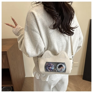Detail of off-white cat-ear ita-bag with transparent window and anime badges