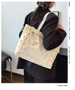 Detail of cream white canvas tote bag with transparent PVC window and ribbon ties