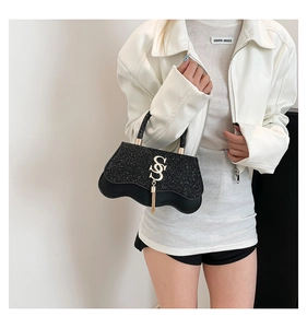 Detail of glitter black handbag with wavy base, golden S buckle and tassel ornament