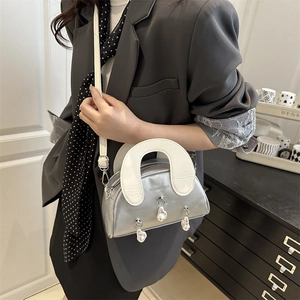 Silver metallic shell handbag with white U-shaped handle and hanging pearl details