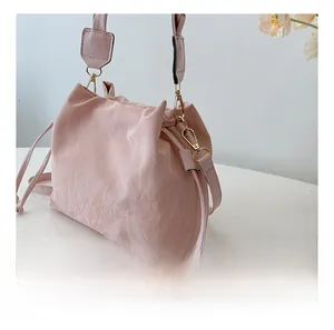 Detail shot of the golden metal hook and pink pleated fabric on a stylish bucket bag
