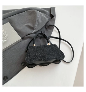 Detail of black sequined handbag with unique wavy base on a minimalist white surface