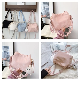 Detailed close-up of pleated texture handbag with woven strap and plush monster charm