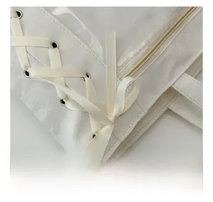Detail of white ita bag featuring side lace-up ribbon bows and metallic eyelets