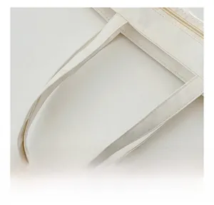 Detail showing the reinforced wide handle and smooth metal zipper on white tote bag