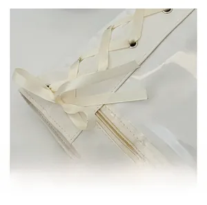 Detail of smooth white zipper closure and elegant cream satin ribbon lacing on bag