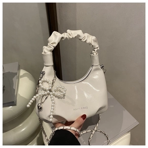 Detail of white scrunchie handle bag with pearl bow pendant and silver chain strap