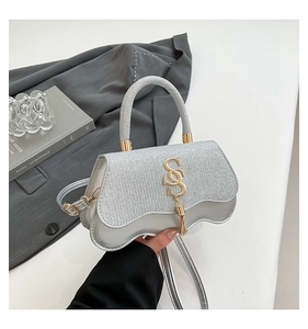 Detail of silver wavy handbag featuring sequined flap and metallic SS logo with tassel